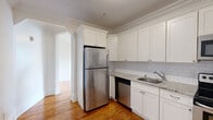 Located at 9201 Kennedy Blvd in North Bergen, NJ, this well-appointed one-bedroom, one-bathroom residence offers a thoughtfully designed layout across a single floor. Warm-toned hardwood flooring flows consistently throughout, complemented by crisp white walls, clean crown molding, and classic white baseboards that lend the space a timeless, polished character.

The living area is generously proportioned, comprising two connected rooms that open to one another through an archway, creating a versatile and expansive common area bathed in natural light from multiple black-framed windows. The kitchen is well-equipped with white shaker-style cabinetry reaching to the ceiling, granite countertops, a white subway tile backsplash, and a full suite of stainless steel appliances including a refrigerator, range, microwave, and dishwasher.

The spacious primary bedroom provides comfortable accommodations with a large window offering views of the surrounding neighborhood greenery. A dedicated closet adds practical storage. The bathroom is neatly finished with large-format grey floor tiles, a full tub-shower combination with white subway tile surround, an accent tile border, and a warm-toned vanity with a granite countertop. The overall ambiance is clean, bright, and move-in ready.
