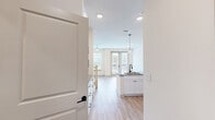 Located in Snellville, GA, this two-story home offers a thoughtfully designed layout spread across two floors. The main level features an open-concept kitchen and living area bathed in natural light from large windows. The kitchen is a standout, showcasing granite countertops, a spacious island with a built-in sink, white shaker cabinetry, stainless steel appliances, and pendant lighting — all set atop light wood-style flooring. A patio with French doors extends the living space outdoors. The upper level hosts two bedrooms, including a primary bedroom with plush carpet flooring, a walk-in closet with built-in shelving, and access to a hallway. The second bedroom features a ceiling fan and ample natural light. Both bathrooms are finished with wood-style flooring, modern vanities with black hardware accents, and framed mirrors. A stacked washer and dryer unit is conveniently located on the upper floor, accessible via a barn-style sliding door. Clean white walls, recessed lighting, and consistent finishes throughout create a cohesive, contemporary aesthetic across the entire home.