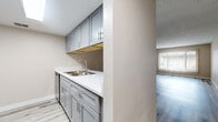 Located at 2601 N 36th St in Phoenix, Arizona, this 2-bedroom, 2-bathroom residence offers a thoughtfully designed single-level layout with modern updates throughout. The open-concept living and dining area is bright and welcoming, featuring light wood-look luxury vinyl plank flooring, textured walls, and a textured ceiling that adds architectural character. Large windows dressed with vertical blinds invite natural light while offering a view of the surrounding neighborhood.

The galley-style kitchen is efficiently arranged with ample storage provided by sleek gray shaker cabinets lining both sides, complemented by white countertops, a stainless steel sink, and stainless steel appliances including a refrigerator and range. Under-cabinet lighting adds a functional finishing touch.

Both bedrooms are generously proportioned with vinyl plank flooring, textured walls, and large closets fitted with sliding panel doors offering substantial storage. The primary bedroom includes a direct en-suite bathroom with a gray vanity, white countertop, large mirror, and toilet, maintaining the home's consistent modern aesthetic.

The two bathrooms are clean and updated, each featuring gray shaker-style vanities with brushed nickel hardware. One bathroom includes a full tub-shower combination with a white surround. Hallways connect the spaces efficiently, contributing to a cohesive and functional floor plan throughout the home.