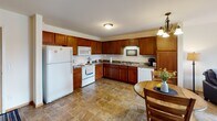 Located at 1000 Opportunity Blvd S in Cambridge, Minnesota, this single-floor residence offers a thoughtfully designed layout that balances functionality and comfort. The open-concept kitchen and dining area serves as the heart of the home, featuring rich warm-toned wood cabinetry, granite-style countertops, tile flooring, and a full suite of white appliances including a refrigerator, range, microwave, and dishwasher. A pendant chandelier illuminates the dining space, which flows naturally into the living room. The living room is carpeted and bright, benefiting from natural light streaming through a sliding glass door that opens to a private balcony with pleasant outdoor views of the surrounding landscape. The bedroom is generously sized with soft carpet, a large window that allows ample natural light, and ample space for furnishings. The full bathroom features tile flooring consistent with the kitchen, warm wood vanity cabinetry, a single-sink vanity with a broad mirror, and a tub/shower combination. A dedicated entryway with a closet provides a welcoming transition into the home. Throughout, the space maintains a clean, neutral palette that creates a warm and inviting atmosphere.