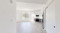 Located at 1100 West Temple Street in Los Angeles, this thoughtfully designed unit offers a clean, contemporary aesthetic throughout. The open-concept main living area seamlessly integrates the living room, dining space, and kitchen into one bright, airy environment. Light wood-tone flooring extends across the space, complementing the crisp white walls and contributing to a fresh, modern atmosphere. Large windows invite generous natural light and offer views of surrounding greenery, enhancing the sense of openness.

The kitchen is well-appointed with a full suite of stainless steel appliances, including a gas range, over-the-range microwave, dishwasher, and a full-size refrigerator. Two-toned cabinetry — white uppers paired with grey lowers — adds visual depth, while a tile backsplash and undermount sink with a matte black faucet deliver refined, contemporary detail.

The bathroom is a standout feature, finished with striking black hexagonal floor tile, a grey vanity with white countertop, matte black hardware, and a large mirror with modern bar lighting above — creating a sleek, spa-like feel. Two closets provide practical storage throughout the unit. The overall ambiance is clean and minimalist, making it an ideal canvas for personalization in the heart of Los Angeles.