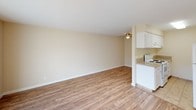 Located at 7051 Bowling Dr in Sacramento, California, this single-floor unit offers a practical and comfortable layout with a clean, neutral aesthetic throughout. The open living area is finished with warm wood-look flooring and features a ceiling fan, creating an airy and functional space. Large sliding glass doors connect the living room to a private outdoor patio, allowing natural light to fill the interior and providing easy outdoor access. The kitchen is positioned adjacent to the living area in an efficient semi-open layout, equipped with white cabinetry, a tile floor, a range, and a full-size refrigerator, offering ample storage and workspace. The bedrooms feature plush carpeting and are bathed in natural light through windows with outdoor views of the surrounding greenery. Each bedroom includes closet space, contributing to comfortable day-to-day living. The bathroom is well-appointed with a tiled tub-and-shower surround accented by a decorative mosaic tile border, a granite-topped vanity, tile flooring, and a large mirror. The unit's consistent warm beige palette and clean finishes create a cohesive, move-in-ready atmosphere throughout.
