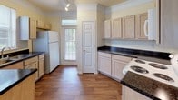 This single-story, 3-bedroom, 2-bathroom residence offers a thoughtfully designed layout across a generous footprint. The expansive living area features warm neutral-toned carpet, a ceiling fan, crown molding, and a charming arched alcove that adds architectural character. Multiple windows flood the space with natural light, creating a bright and welcoming atmosphere throughout.

The kitchen is well-equipped with light wood cabinetry, dark granite-style countertops, wood-look vinyl flooring, and white appliances including a range, built-in microwave, and refrigerator. A window overlooking the outdoors and direct access to an additional room enhance both function and flow.

Each of the three bedrooms is carpeted and features large windows that bring in ample daylight and outdoor views. The primary bedroom includes access to a spacious walk-in closet outfitted with wire shelving systems for generous storage.

Both bathrooms are finished with wood-look vinyl flooring, white vanities, and full tub-shower combinations with tiled surrounds, offering a clean and functional design. Consistent warm beige wall tones and white trim throughout the home create a cohesive, neutral palette that is easy to personalize.