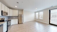 Located at 80 S 18th St. in Columbus, OH, this 2-bedroom, 1-bathroom unit offers a thoughtfully designed single-floor layout with modern finishes. The open-concept living and kitchen area is anchored by light hardwood-style flooring that flows throughout the main spaces, creating a bright and cohesive feel. Natural light pours in through multiple windows, enhancing the airy, neutral color palette of soft whites and warm beiges.

The well-appointed kitchen is a standout feature, boasting white shaker-style cabinetry, granite countertops, a subway tile backsplash, and a full suite of stainless steel appliances including a refrigerator, range, microwave, and dishwasher. A pendant light adds a modern touch above the workspace. The kitchen opens seamlessly into the living area, which includes a glazed door providing additional access and natural light.

Both bedrooms feature plush carpeting and are finished with clean, neutral walls. The primary bedroom connects to a dedicated closet outfitted with wire shelving systems for ample storage. The bathroom is well-proportioned, featuring granite countertops, an undermount sink, and wood-look tile flooring that complements the rest of the unit. The overall design is clean, contemporary, and move-in ready.