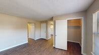 This two-bedroom, one-bathroom single-floor residence in Huntsville, Alabama offers a practical and comfortable layout across a well-utilized footprint. Dark hardwood-style flooring runs throughout the main living areas, hallways, kitchen, and bathroom, lending a cohesive and polished look to the home.

The living room is bright and open, featuring a large window that invites generous natural light and a textured ceiling. It flows seamlessly into the combined kitchen and dining area, where a chandelier-lit dining space sits beside a sizable window with outdoor views. The kitchen is outfitted with white cabinetry, ample counter space, a coil-top range, and a full-size refrigerator, all arranged in an efficient L-shaped configuration.

Both bedrooms are carpeted for comfort and each features a ceiling fan with light fixture and a window for natural ventilation. The primary bedroom includes closet access, and throughout the home, an impressive number of closets—totaling ten—provides exceptional storage capacity.

The bathroom is clean and functional, featuring a shower/tub combo and hardwood-style flooring consistent with the rest of the home. Two hallways connect the rooms efficiently, contributing to a logical and easy-to-navigate floor plan. The neutral warm-beige wall tones throughout create a calm, welcoming ambiance.