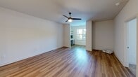 Located at 1000 Lassen Dr in Knightdale, NC, this well-appointed 2-bedroom, 2-bathroom residence offers a thoughtfully designed single-floor layout. The kitchen is a standout feature, showcasing white shaker-style cabinetry with matte black hardware, white quartz countertops, stainless steel appliances including a refrigerator and range with a wall-mounted hood, a peninsula with a undermount sink, and warm wood-look flooring that flows throughout the main living areas. The open living room extends into a dedicated nook with built-in cabinetry, a desk, and floating shelves — an ideal home office or study area — with a window that brings in natural light. Both bedrooms are carpeted and equipped with ceiling fans. The primary bedroom offers generous proportions and a bright window with outdoor views. The secondary bedroom includes a double closet and ceiling fan. The bathrooms are finished with gray shaker vanities and white quartz countertops. One bathroom features a walk-in glass-enclosed shower, while the other includes a full tub-shower combination with a built-in linen closet nearby. Clean white walls and consistent finishes throughout give the home a cohesive, modern aesthetic.
