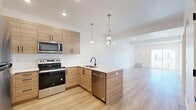 Located at 1126 W 250 S in American Fork, Utah, this thoughtfully designed one-bedroom, one-bathroom unit offers a clean, modern aesthetic throughout its well-utilized single floor. Light wood-tone luxury vinyl plank flooring flows seamlessly through the open-concept living and kitchen areas, creating a bright and cohesive atmosphere.

The kitchen is a standout feature, showcasing warm wood cabinetry, a peninsula with a white countertop and undermount sink, and a full suite of stainless steel appliances including a range, microwave, dishwasher, and refrigerator. Pendant lighting above the peninsula and a chandelier above the adjacent dining area add stylish illumination to the space. The living room is open and airy with recessed lighting and easy access to a private balcony.

The bedroom offers plush carpeting, a natural window view, and a double-door closet, complemented by two additional closets elsewhere in the unit for generous storage. The full bathroom features a clean, contemporary design with a wood-toned vanity, white countertop, black hardware accents, and a tub-shower combination. Crisp white walls throughout enhance the sense of openness and light in this well-appointed home.