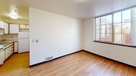 Located at 920 NW Kearney St in Portland, Oregon, this efficiently designed studio unit sits in the heart of the Pearl District. The main living area features light wood-look laminate flooring, crisp white walls, and dark baseboards that provide a clean, modern contrast. A grid-paned window allows natural light to pour in while offering views of the surrounding urban streetscape, adding a sense of openness to the compact footprint.

The layout includes a sliding-door closet and a dedicated entry door with a keypad lock, providing both storage and security. The kitchen is integrated into the unit, offering functional prep and cooking space. The bathroom is equipped with a full tub and shower combination, complete with stainless steel grab bars and a curtain rod, reflecting a practical and accessible design.

Consistent wood-look flooring runs throughout, tying the spaces together cohesively. Flush-mount ceiling light fixtures and in-floor heating vents contribute to the unit's practical amenities. The overall aesthetic is clean and understated, making it a well-suited space for those seeking a streamlined urban living environment in one of Portland's most walkable and sought-after neighborhoods.