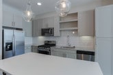 Located at 7080 Sweet Creek Rd in Johns Creek, Georgia, this single-floor residence presents a clean, contemporary design highlighted by neutral tones, quality finishes, and a cohesive aesthetic throughout. The open-concept living area is bathed in natural light from large windows dressed with horizontal blinds, and features durable wood-look flooring that flows seamlessly toward the kitchen. A private entry door with transom window adds a welcoming architectural touch.

The kitchen is a standout feature, equipped with stainless steel appliances including a gas range, built-in microwave, and French door refrigerator. Gray shaker-style cabinetry pairs with white subway tile backsplash and granite countertops, while a generous island with a crisp white surface offers additional workspace and storage. Pendant lighting adds a refined touch overhead.

The bedroom areas feature plush patterned carpeting and ample natural light. The primary bedroom connects directly to a walk-in closet outfitted with wire shelving, as well as a private bathroom featuring a glass-enclosed shower with large-format tile surround, built-in bench, and elegant overhead lighting. A secondary bathroom with light tile flooring provides additional convenience.
