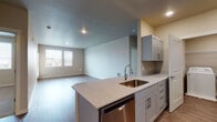 Located at 3815 SW Murray Blvd in Beaverton, Oregon, this well-appointed single-floor residence offers a thoughtfully designed open-concept layout that seamlessly connects the kitchen and living areas. The kitchen serves as the centerpiece of the space, showcasing a peninsula with granite countertops, a stainless steel undermount sink, and a full suite of stainless steel appliances including a refrigerator, range, microwave, and dishwasher. Gray shaker-style cabinetry provides ample storage and lends a clean, contemporary aesthetic throughout. Recessed lighting illuminates the kitchen and living areas, which are finished with durable wood-style flooring that runs continuously through the main living spaces. The expansive living area benefits from natural light streaming through multiple windows. The bathroom features granite countertops, a wide vanity mirror, and a full tub-shower combination. A dedicated in-unit laundry area with a full-size washer and dryer adds everyday convenience. Neutral wall tones and clean finishes throughout create a bright, welcoming atmosphere that is both functional and modern, making this Beaverton residence a practical and attractive place to call home.