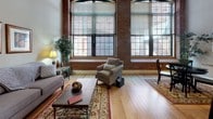 Located at 300 Canal in Lawrence, MA, this single-floor loft-style residence showcases a striking blend of historic industrial character and modern finishes. The expansive living area is defined by soaring ceilings, exposed brick walls, and oversized factory-style windows that flood the space with abundant natural light while offering views of the surrounding neighborhood. Light hardwood flooring runs throughout, tying each area together seamlessly.

The kitchen is thoughtfully designed with warm wood cabinetry, granite countertops, stainless steel appliances including a gas range and French door refrigerator, and a peninsula with bar seating — ideal for casual dining or entertaining. Exposed ductwork and pendant lighting above the peninsula reinforce the loft's industrial aesthetic.

The bedrooms offer a quiet retreat, featuring neutral tones, high ceilings, clerestory windows, and generous closet space. One bedroom includes dual sliding closets, providing ample storage.

A hallway utility area accommodates a stacked washer and dryer unit alongside a vanity with granite countertop and tile flooring, adding convenience within the unit. Exposed structural columns punctuate the interior, serving as a nod to the building's mill heritage while contributing to the distinctive character of this well-crafted urban residence.