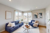 Located at 55 Seely School Dr in Groton, CT, this thoughtfully designed one-bedroom, one-bathroom residence offers a comfortable and modern living experience across a single floor. The open-concept layout seamlessly connects the kitchen, dining area, and living room, creating a bright and airy atmosphere enhanced by large windows that flood the space with natural light and offer pleasant outdoor views.

The kitchen is a standout feature, boasting sleek white upper cabinetry paired with warm wood-toned lower cabinets, crisp white quartz countertops, stainless steel appliances including a refrigerator, dishwasher, and range, and a central island with bar seating illuminated by stylish pendant lights. Light hardwood flooring ties the kitchen and living areas together seamlessly.

The living room is generously proportioned, featuring recessed lighting, large windows with sheer drapes, and direct access to a private balcony. The bedroom offers a cozy retreat with plush carpeting and ample space for a full furniture arrangement. Two closets provide excellent storage throughout the unit.

The bathroom is elegantly finished with large-format marble-look tile flooring, a wood-grain vanity with white countertop, a framed mirror, and a tall linen storage cabinet. Additional conveniences include a dedicated laundry area and a welcoming entrance hallway.