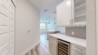 Located in Melbourne, FL, this well-appointed one-bedroom, one-bathroom residence offers a thoughtfully designed layout with modern finishes throughout. Light-toned wood-look flooring flows seamlessly across the entire space, complementing the bright, neutral color palette that creates an airy and welcoming ambiance.

The open-concept kitchen, dining, and living area serves as the heart of the home. The kitchen is outfitted with white shaker-style upper cabinets, grey lower cabinets, a grey subway tile backsplash, quartz countertops, and a full suite of stainless steel appliances including a smart refrigerator, electric range, and built-in microwave. A spacious center island with a farmhouse-style sink and pendant lighting above adds both functionality and style. A built-in wine cooler provides an upscale touch. The living area features a ceiling fan and direct access to a private balcony through glass-paned doors.

The generously sized primary bedroom includes a ceiling fan, natural light from multiple windows, and a stylish barn door leading to a walk-in closet with custom shelving and built-in storage. The bathroom features a glass-enclosed walk-in shower with tile surround, a single-sink vanity with quartz countertop, and wood-look flooring. Additional conveniences include a dedicated laundry area, pantry, and hallway connecting all spaces efficiently.