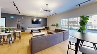 Located at 20 Rue De La Bonne Renomée in Gatineau, QC, this well-appointed communal amenity space is thoughtfully designed to foster social interaction and relaxation. The single-floor layout encompasses a combined living and dining area, offering a seamless flow between distinct functional zones.

The entrance welcomes visitors with a refined lounge nook, defined by elegant slatted wood partitioning, rich burgundy accent chairs, and lush greenery set against a charcoal feature wall. Recessed lighting and a sculptural pendant fixture enhance the sophisticated ambiance.

The living zone features warm hardwood flooring, a large sectional sofa, a pool table, and a wall-mounted flat-screen TV, all anchored by a striking multi-bulb chandelier. Track lighting and a large sliding glass door leading to an outdoor balcony bring in generous natural light and outdoor views.

The dining area is bright and airy, with light hardwood floors, multiple high-top tables and stools, and a dramatic living moss wall installation that adds a vibrant natural accent. Large windows overlook the balcony, filling the space with daylight. A cozy sun-drenched nook with floor-to-ceiling sliding glass doors offers panoramic outdoor views, ideal for a quiet retreat. A central kitchenette with wood cabinetry provides practical convenience throughout the space.
