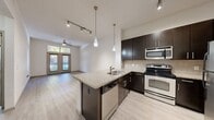Located at 2616 Bagby Street in Houston's vibrant Montrose neighborhood, this one-bedroom, one-bathroom unit at City Place Montrose offers a well-designed, efficiently laid-out living space. Light wood-style flooring runs throughout, creating a cohesive and contemporary feel.

The open-concept kitchen is a standout feature, equipped with dark espresso cabinetry, granite countertops, a peninsula with a built-in sink, stainless steel appliances including a refrigerator, electric range, microwave, and dishwasher, and stylish pendant lighting. Track lighting enhances the functional flow between the kitchen and living area.

The living room is bright and welcoming, anchored by a set of French doors with transom windows above that invite natural light and provide views of the surrounding greenery. A ceiling fan adds comfort to the space.

The bedroom is generously sized, featuring a large window with natural light and direct access to a walk-in closet outfitted with wire shelving and organizational storage on multiple levels.

The bathroom is clean and functional, offering a tiled tub-shower combination, a dark-framed vanity with a light countertop, a large mirror, and light wood-style flooring consistent with the rest of the unit. A hallway connects the main living areas efficiently, completing this thoughtfully arranged home.