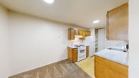 Located at 2462 Bow Ct in South Bend, Indiana, this single-floor unit offers a straightforward, functional layout designed for comfortable everyday living. The floor plan, as revealed through the 3D model, arranges the kitchen centrally, with living and sleeping areas extending to either side, creating a logical and efficient flow throughout the space.

The galley-style kitchen is well-equipped, featuring warm honey-toned wood cabinetry that lines both walls, providing generous storage space. A white gas range, refrigerator, and stainless steel sink are included, along with light-toned countertops and tile flooring. Notably, in-unit washer and dryer hookups are integrated directly within the kitchen area, adding a practical convenience. A built-in pantry cabinet offers additional storage.

The living area is open and spacious, with neutral-toned carpet throughout and cream-colored walls that create a clean, bright atmosphere. A large window fitted with vertical blinds allows natural light to fill the space and provides an exterior view, while a door offers direct outdoor access.

The bedrooms are carpeted and feature neutral walls, with windows fitted with blinds allowing natural light and views of the surrounding greenery. Overall, the space maintains a simple, clean aesthetic with an emphasis on practicality and functionality.
