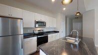Located at 7325 Liberty Summit Dr in Powell, Ohio, this single-story home offers a well-designed, open layout with thoughtful finishes throughout. The kitchen serves as a central highlight, featuring crisp white shaker cabinetry, dark stone countertops, a central island with a built-in sink, and a full suite of stainless steel appliances including a refrigerator, electric range, and over-the-range microwave. Stylish pendant lighting above the island adds a modern touch, while recessed lighting and a window with natural light complete the space. Rich hardwood-style flooring runs through the kitchen and wet areas, grounding the open-concept design.

The living area is expansive and airy, defined by soaring vaulted ceilings and large glass doors that invite natural light and outdoor views. Plush carpet adds warmth and comfort underfoot.

The bedrooms are carpeted and well-proportioned, with one offering access to a spacious walk-in closet complete with wire shelving systems. Two full bathrooms are finished consistently with white cabinetry, dark stone countertops, and hardwood-style flooring — one with a walk-in shower and the other with a tub-shower combo. A dedicated laundry room with washer and dryer hookups rounds out this functional and well-appointed home.