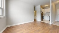 Located at 1379 Princess St in Kingston, Ontario, this efficiently designed one-bedroom, one-bathroom unit makes thoughtful use of its space across a single floor. The interior is finished with warm hardwood-style flooring throughout the main living areas and bedroom, complemented by neutral grey-toned walls that create a clean, bright aesthetic.

The living room is a welcoming space anchored by a wide, multi-pane window that frames outdoor views of mature trees, allowing generous natural light to fill the room. A baseboard radiator ensures comfortable heating during Kingston's colder seasons. The layout flows naturally into the kitchen, which features white cabinetry, a stainless steel refrigerator, and a stove, offering a practical and tidy cooking space with tile flooring.

The bedroom is a well-proportioned room with its own window overlooking greenery, a closet with panel doors, and a radiator — providing both natural light and warmth. The unit benefits from a total of three closets, offering excellent storage throughout.

The bathroom is clean and simply appointed, featuring a full soaker tub with glossy white subway tile surround and chrome fixtures. The entrance provides a welcoming threshold into the unit. Overall, this space offers a straightforward, functional layout with consistent finishes throughout.