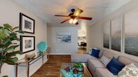 This single-story, 2-bedroom, 2-bathroom residence in Ridgeland, Mississippi offers a traditional layout with a warm, comfortable ambiance throughout. The living area features wood-style plank flooring, a ceiling fan with light fixture, and a tiled fireplace that serves as a natural focal point. The space flows directly into a dedicated dining area, which is illuminated by a stylish overhead light fixture and comfortably accommodates a round dining table. The kitchen is outfitted with ample white cabinetry with light wood accents, a double-basin sink, dishwasher, and electric range, all complemented by wood-style flooring. A secondary living or flex space provides additional room for various uses and features carpet flooring and natural light from a large window. Both bedrooms are carpeted and include ceiling fans, with windows allowing natural light. Each of the two full bathrooms includes a single-sink vanity with wood-tone cabinetry, a tub-shower combination, and wood-style flooring. Throughout the residence, neutral wall tones and textured ceilings contribute to a cohesive, traditional aesthetic.