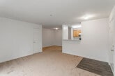 This single-floor residence offers a well-organized layout that balances open communal spaces with defined private areas. The living room is generously sized, finished with neutral-toned carpet and cream walls that create a bright, welcoming atmosphere. A pass-through counter connects the living area to the kitchen, maintaining an open feel while providing a functional divide. The front entry opens directly into this main living space, which also transitions to a private balcony through sliding glass doors, offering pleasant views of surrounding foliage.

The galley-style kitchen is efficiently arranged with warm honey-toned wood cabinetry lining both walls, light speckled countertops, wood-look vinyl flooring, and white appliances including a range and refrigerator. A dishwasher is also present, and the layout maximizes storage and counter space throughout.

The bedrooms are carpeted and bathed in natural light through large windows that frame outdoor tree views. Each room offers a calm, neutral palette with adequate closet space. One bedroom features a sliding glass door accessing the balcony, while others include standard double-door or walk-in style closets.

The bathroom includes a tub-shower combination with tile surround, wood-look flooring, and clean white fixtures, providing a functional and tidy finish to the unit.