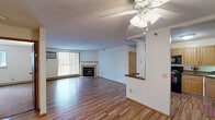 This single-floor residence offers a well-organized and functional layout designed for comfortable everyday living. The open living room serves as the heart of the space, featuring warm hardwood-style flooring, a ceiling fan with integrated lighting, a textured ceiling, and a tiled fireplace that anchors the room. A large sliding glass door floods the area with natural light and provides access to an outdoor balcony, while vertical blinds offer privacy when desired.

The kitchen is efficiently designed with warm wood cabinetry, dark countertops, and black appliances including a refrigerator, range, microwave, and dishwasher. A pass-through breakfast bar connects the kitchen to the living area, enhancing the open flow of the space.

The unit includes two bedrooms, each carpeted for comfort. One bedroom features a sliding-door closet with built-in shelving and hanging rods, while both rooms include windows that bring in natural light and are equipped with baseboard heating and wall-unit air conditioning for year-round climate control.

Two bathrooms serve the unit. One offers a pedestal sink, a walk-in corner shower with glass doors, and tile flooring. The second bathroom features a vanity with storage, a toilet, and a full tub-shower combination. Both bathrooms are finished with tile flooring, contributing to a clean and practical aesthetic throughout the home.
