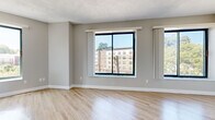 Located at 170 Washington St in Haverhill, MA, this one-bedroom, one-bathroom residence offers a well-designed single-floor layout with modern finishes throughout. Light wood-tone flooring runs continuously across the space, complementing the neutral gray and white color palette that lends a clean, contemporary feel.

The open-concept living room and kitchen area serves as the heart of the unit. The living area is defined by large sliding windows that invite abundant natural light and offer views of the surrounding Haverhill streetscape. A distinctive exposed concrete column adds an architectural character to the space. The kitchen features white shaker-style cabinetry, quartz countertops with a breakfast bar overhang, a white tile backsplash, and a full suite of stainless steel appliances including a refrigerator, range, and over-the-range microwave.

The bedroom is a comfortable, well-proportioned room with its own window providing natural light and outdoor views, along with a dedicated closet offering built-in shelving and hanging storage. The bathroom includes a full tub and shower combination with chrome fixtures. The overall layout is efficient and functional, making excellent use of the available footprint to deliver a bright, livable, and stylishly appointed residence.