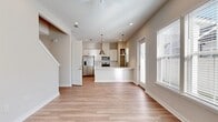 This two-story home offers a thoughtfully designed layout spread across two floors, with the main level comprising the majority of the living space. The open-concept kitchen and living area anchors the first floor, featuring light hardwood-style flooring, recessed lighting, and a ceiling fan. The kitchen is outfitted with white shaker cabinetry, stainless steel appliances including a refrigerator, range, and microwave, a white quartz island with an undermount sink, and stylish pendant lighting. Large windows allow natural light to fill the combined living and dining space.

A clean, neutral-toned hallway connects the main living areas to the bedrooms and bathrooms. The three bathrooms include a primary bath with a double-sink vanity featuring white cabinetry, quartz countertops, and a glass-enclosed walk-in shower with a clerestory window. Bedrooms feature either hardwood-style flooring or plush carpet and are brightened by windows with blinds. One bedroom includes a built-in nook and staircase access, while the primary bedroom is served by a walk-in closet with wire shelving. The attached garage provides additional utility with an automatic opener and concrete flooring.