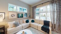 Located at 2509 N. Davidson St. in Charlotte's vibrant NoDa neighborhood, this single-floor residence offers a thoughtfully designed layout with contemporary finishes throughout. The galley-style kitchen is a standout feature, outfitted with floor-to-ceiling white shaker cabinetry, quartz countertops, a white subway tile backsplash, and a full suite of stainless steel appliances including a French door refrigerator, electric range, and built-in microwave. A peninsula with an undermount sink and pendant lighting adds both function and style, while light wood-tone flooring ties the space together seamlessly. The living area is bright and inviting, benefiting from oversized windows that frame outdoor views and allow abundant natural light to fill the room. A curated gallery wall adds a refined artistic touch to the space. The bedrooms are generously proportioned, each featuring plush carpeting, large windows with exterior views, and ceiling fans. The primary bathroom is finished with large-format marble-style tile in the walk-in glass-enclosed shower, complemented by neutral toned walls and light flooring. Throughout the residence, a cohesive neutral palette, modern fixtures, and clean architectural lines create a polished and comfortable living environment.