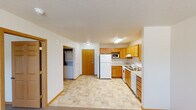 This single-floor unit offers a functional and straightforward layout with consistent design details carried throughout. The kitchen is a standout feature, outfitted with warm honey-toned oak cabinetry spanning both upper and lower sections, providing generous storage. White appliances include a full-size refrigerator, electric range, dishwasher, and built-in microwave. Light tile flooring runs through the kitchen and extends into the main entryway and utility areas, offering easy maintenance underfoot.

Adjacent to the kitchen, a dedicated alcove houses a stacked washer and dryer unit, adding in-unit laundry convenience. An exterior door is located nearby, providing a secondary point of entry. The living area transitions to neutral-toned carpeting and is brightened by a window fitted with horizontal blinds. A wall-mounted HVAC unit provides climate control directly within the space.

The bathroom features a single-sink oak vanity with a white countertop, mirrored medicine cabinet, an additional wall-mounted storage cabinet, and tile flooring that coordinates with the rest of the unit. Textured ceilings and warm oak door and window trim are consistent throughout, giving the space a cohesive, practical finish.