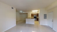 This single-story residence is finished with large-format, high-gloss white ceramic tile flooring that runs continuously throughout, lending a clean and cohesive aesthetic to every room. The open-concept living and kitchen area forms the heart of the space, where a peninsula with granite countertops serves as a natural divider. The kitchen is well-appointed with dark wood cabinetry, matching granite countertops, a stainless steel electric range, and an over-the-range microwave. The living area extends toward a sliding glass door that opens to a private outdoor area with greenery visible beyond.

The bedrooms are bright and neutrally finished, with cream-toned walls and generous windows fitted with blinds, allowing natural light while maintaining privacy. The larger bedroom benefits from two windows and a dedicated closet with built-in shelving. A second bedroom offers a window with an outdoor view. Each bedroom connects to a full bathroom; both bathrooms feature soaking tubs with tile surrounds, and one includes a dark wood vanity with an integrated sink. The overall ambiance is clean, minimal, and move-in ready.