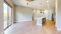 Located at 1120 Shady Ln in Austin, TX, this thoughtfully designed one-bedroom, two-bathroom unit offers a bright and modern living experience. Light wood-style flooring flows throughout the entire space, creating a cohesive and airy feel.

The open-concept living and kitchen area forms the heart of the unit. The kitchen is outfitted with white cabinetry, a herringbone-style tile backsplash, stainless steel appliances including a refrigerator, electric range, microwave, and dishwasher, and a generous center island with a clean white countertop illuminated by pendant lighting. A ceiling fan anchors the living area, which opens to a private balcony offering views of mature trees and surrounding greenery.

The bedroom is a comfortable, well-lit retreat featuring large windows that bring in abundant natural light and tree-lined outdoor views. It connects to a dedicated closet with built-in shelving and hanging storage, as well as a private en-suite bathroom complete with a glass-enclosed walk-in shower and a sleek vanity with a white countertop and modern fixtures. A second full bathroom features an additional vanity and toilet, providing convenience for guests. The unit's clean, neutral palette and contemporary finishes make it a refined and functional home.