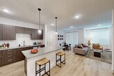 This well-designed 2-bedroom, 3-bathroom single-floor residence offers a thoughtful open-concept layout that seamlessly connects the kitchen, dining, and living areas. The kitchen is a standout feature, showcasing rich dark-wood cabinetry, granite countertops, stainless steel appliances, and a large center island with bar seating accented by stylish pendant lighting — ideal for both everyday living and entertaining. Light-toned hardwood flooring flows throughout the main living areas, enhancing the bright, airy ambiance created by recessed lighting and large windows.

The spacious living room provides a comfortable gathering space with access to natural light through sliding glass doors. Both bedrooms are carpeted and feature ceiling fans, generous closet space, and large windows. The primary bedroom includes a walk-in closet with dual hanging rods and shelving. Each of the three bathrooms is finished with granite vanity countertops and tile work; one features a soaking tub with a tiled surround, while another offers a glass-enclosed walk-in shower.

Additional conveniences include a dedicated laundry area, a utility room, and ample closet storage throughout. The clean, neutral color palette and modern finishes create a cohesive and contemporary atmosphere across the entire residence.