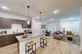This well-designed 2-bedroom, 3-bathroom single-floor residence offers a thoughtful open-concept layout that seamlessly connects the kitchen, dining, and living areas. The kitchen is a standout feature, showcasing rich dark-wood cabinetry, granite countertops, stainless steel appliances, and a large center island with bar seating accented by stylish pendant lighting — ideal for both everyday living and entertaining. Light-toned hardwood flooring flows throughout the main living areas, enhancing the bright, airy ambiance created by recessed lighting and large windows.

The spacious living room provides a comfortable gathering space with access to natural light through sliding glass doors. Both bedrooms are carpeted and feature ceiling fans, generous closet space, and large windows. The primary bedroom includes a walk-in closet with dual hanging rods and shelving. Each of the three bathrooms is finished with granite vanity countertops and tile work; one features a soaking tub with a tiled surround, while another offers a glass-enclosed walk-in shower.

Additional conveniences include a dedicated laundry area, a utility room, and ample closet storage throughout. The clean, neutral color palette and modern finishes create a cohesive and contemporary atmosphere across the entire residence.