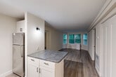 Located at 144 Larkin Way in South Burlington, Vermont, this single-floor, 2-bedroom, 3-bathroom residence offers a thoughtfully designed layout with clean, modern finishes throughout. The open-concept living and dining area is anchored by a charming bay window that floods the space with natural light and frames lush, green outdoor views. Rich, dark hardwood-style flooring runs seamlessly through the main living areas and bedrooms, adding warmth and cohesion to the interior.

The kitchen features white cabinetry with matte black hardware, dark countertops, stainless steel appliances including a refrigerator and range, a built-in microwave, and a peninsula that provides additional prep space and a natural transition to the living area. Track lighting overhead ensures excellent task illumination.

Both bedrooms are comfortably sized, each equipped with windows offering views of surrounding greenery, providing a calm and private atmosphere. The primary bedroom offers a generous footprint ideal for a full bedroom suite. Three closets are distributed throughout the unit for ample storage.

The bathrooms are finished in a clean, neutral palette, with one featuring a full soaking tub and shower combination with accessibility grab bars and tile flooring. A connecting hallway ties the layout together efficiently, making this a practical and well-organized residence.
