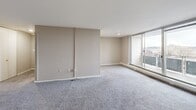 Located at 660 Boas St in Harrisburg, PA, this three-bedroom, one-bathroom residence offers a well-organized single-floor layout with a functional and straightforward design throughout. The living area is generously sized, finished with plush gray carpeting and neutral taupe walls, and opens to a private balcony through a sliding glass door, allowing an abundance of natural light and views of the surrounding cityscape. The kitchen is set just off the main living space and features white cabinetry, a dark dishwasher, and hard-surface flooring, providing a clean and practical workspace. The expansive primary bedroom is a standout feature of the home, offering ample square footage, a wall of built-in bifold closets with gold hardware, and large windows with views of the Harrisburg skyline. A second bedroom mirrors this bright quality with oversized windows, baseboard heating, and a wall-mounted AC unit. The dedicated walk-in closet provides generous storage with dual hanging rods. The bathroom retains a retro character, showcasing sky-blue tile wainscoting, a matching blue sink, a white countertop, and a mirrored medicine cabinet. A connecting hallway ties the rooms together cohesively, completing this well-structured residence.