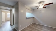 Located at 4225 Mangum Rd in Houston, Texas, this single-story unit offers a well-organized layout with consistent modern updates throughout. The living area greets you at the entry with rich, dark-toned laminate flooring, neutral-toned walls, and a window fitted with blinds that invites natural light into the space.

The kitchen is designed as a galley-style space featuring light wood-look flooring, white cabinetry, laminate countertops, and a full suite of white appliances including a refrigerator, range, and dishwasher. A pass-through window with a built-in countertop shelf connects the kitchen to the adjacent dining or living area, enhancing the open feel between spaces.

The bedrooms are finished with light gray laminate flooring and are each equipped with ceiling fans with integrated lighting. Windows with blinds provide natural light and views of the surrounding greenery. The rooms offer clean, neutral walls suitable for a variety of uses.

The bathroom features a full tub and shower combination with white tile surround and chrome fixtures, complemented by matching light flooring. A dedicated laundry area houses a stacked washer and dryer unit alongside built-in shelving, providing convenient in-unit laundry and additional storage. The overall aesthetic is clean, functional, and move-in ready.