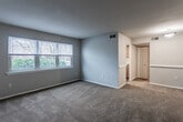 Located at 917 Lake Village Dr in Chesapeake, VA, this single-floor residence offers a practical and comfortable layout designed for everyday living. The spacious living area is finished with warm beige carpeting and neutral gray walls, creating a clean, versatile backdrop. A window along one wall invites natural light and provides views of the surrounding neighborhood. The entry features durable wood-look flooring that transitions into the carpeted main living space.

The galley-style kitchen is well-appointed with warm oak cabinetry, light granite-style countertops, a stainless steel sink, and a gas range. A window above the counter brightens the space with natural light, while wood-look flooring adds a cohesive, practical finish.

The bedrooms are carpeted and finished in soft neutral tones. Each room includes closet storage — one featuring a double bifold-door closet with a full hanging rod and shelving, and another with a walk-in style closet, offering generous storage capacity.

The bathroom is straightforward and clean, featuring a full tub-shower combination with grab bar support, a toilet, and wood-look tile flooring. The overall ambiance throughout the residence is calm and neutral, providing a functional, move-in-ready environment.