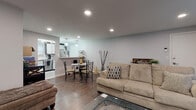 Located at 126 New Britain Ave in Plainville, CT, this single-floor unit offers a well-designed layout with a cohesive, modern aesthetic throughout. The open-concept living and dining area is anchored by rich hardwood-style flooring, recessed lighting, and a bright, neutral color palette. The living room provides comfortable space for relaxing, with a large window allowing natural light to filter in alongside a wall-mounted HVAC unit. A dining area with pendant lighting sits seamlessly between the living space and the kitchen, creating an inviting flow for everyday living and entertaining.

The kitchen is a standout feature, outfitted with white shaker-style cabinetry accented by gold hardware and dark upper trim. Stainless steel appliances — including a range, microwave, dishwasher, and refrigerator — complement the classic white subway tile backsplash and light tile flooring.

The primary bedroom features warm hardwood-style floors, a bold accent wall in deep gray-blue, natural window light, and a stylish sputnik-style ceiling fixture. A second bedroom offers the same flooring and a clean, functional layout. The bathroom is neatly appointed with a white vanity and a shower-tub combination dressed with a decorative curtain, maintaining the unit's clean, contemporary feel throughout.
