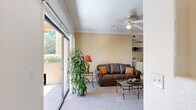 This single-floor, 2-bedroom, 2-bathroom home offers a thoughtfully designed layout that maximizes comfort and functionality. The living room serves as the heart of the home, featuring warm neutral tones, plush carpeting, a ceiling fan, and crown molding. Large sliding glass doors flood the space with natural light and open directly onto a private patio overlooking mature trees and landscaping, creating a seamless indoor-outdoor connection.

The kitchen is efficiently arranged in a U-shaped configuration, outfitted with warm wood cabinetry, granite-style countertops, tile flooring, and black appliances including a gas range, built-in microwave, dishwasher, and refrigerator. Adjacent to the kitchen, the dining area accommodates intimate gatherings and features a built-in corner shelving unit for added storage and display.

The primary bedroom is generously sized, offering carpeted floors, a large window with outdoor views, and ample room for furnishings. The second bedroom is equally comfortable, also carpeted and naturally lit through wide windows with vertical blinds. Both bathrooms are finished with tile flooring, tile-surround tub-shower combinations, wood vanity cabinetry, and wide mirrors. A hallway and closet complete the layout, contributing to practical day-to-day storage throughout the home.