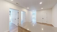 Located at 1 Atlantic St in downtown Stamford, Connecticut, this single-floor unit showcases a clean, contemporary design with modern finishes throughout. The open-concept kitchen is a standout feature, equipped with warm wood-toned cabinetry, quartz countertops, a central island, and stainless steel appliances including a refrigerator, dishwasher, and range. Recessed lighting illuminates the space efficiently throughout.

The living area is generously sized and filled with natural light from large, architecturally distinctive leaded-glass windows framed in black, lending a sophisticated character to the bright, white-walled interior. Wide-plank wood-look flooring flows consistently across the living spaces, hallways, and bedrooms, creating a cohesive and warm aesthetic.

The unit includes multiple rooms accessible via wide hallways, with one bedroom featuring a window and direct access to additional spaces. A double-door closet provides ample storage. The bathrooms are well-appointed, featuring marble-look tile flooring, wood-toned vanities, and a full tub-shower combination with clean white tile surround. A separate water closet adds convenience.

Overall, the space presents a fresh, move-in-ready environment with a neutral palette, modern hardware with matte black accents, and thoughtful layout that balances open living with defined private areas.