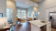 Located at 111 Bridge St in Franklin, Tennessee, this single-floor residence showcases a thoughtfully designed open-concept layout with impressively tall ceilings that lend an airy, expansive feel throughout. Rich hardwood flooring flows seamlessly from room to room, grounding the space with warmth and continuity.

The gourmet kitchen is a standout feature, outfitted with crisp white shaker cabinetry extending to ceiling height, granite countertops, a full suite of stainless steel appliances, a subway tile backsplash, and a large central island with bar seating — ideal for both casual dining and entertaining. Pendant lighting adds a polished finishing touch overhead.

The living area is bathed in natural light through oversized windows that reach toward the soaring ceiling, creating a bright and welcoming atmosphere. A ceiling fan adds comfort to the space.

Two generously sized bedrooms offer serene retreats, each with tall ceilings and hardwood flooring. One bedroom benefits from a large window framing lush outdoor greenery. The primary bathroom features a dual-sink granite vanity, a soaking tub with tile surround, built-in open shelving, and access to a walk-in closet. A second full bathroom provides a tiled tub-shower combination and granite countertops, rounding out this refined and functional home.