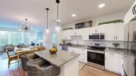 Located at 105 Constantine Rd in Garden City, GA, this well-appointed 2-bedroom, 2-bathroom residence offers a thoughtfully designed single-floor layout with modern finishes throughout. The open-concept kitchen serves as the centerpiece of the home, showcasing crisp white shaker cabinetry, granite countertops with a herringbone tile backsplash, and a full suite of stainless steel appliances. A generously sized island with seating flows seamlessly into the living area, which is bathed in natural light from large windows overlooking lush greenery. Warm-toned hardwood-style flooring runs through the main living areas, adding a cohesive and inviting feel. The living room features a ceiling fan and ample space for comfortable furnishings. Both bedrooms are carpeted and well-lit, each with ceiling fans and windows that bring in natural light. The spacious primary bedroom connects to a private en-suite bathroom complete with granite vanity counters, white cabinetry, a glass-enclosed shower, and wood-look flooring. A walk-in closet with multi-tiered wire shelving provides excellent storage. The second bathroom mirrors the same refined aesthetic with a granite vanity and large framed mirror. Two closets throughout the home ensure practical storage solutions for everyday living.