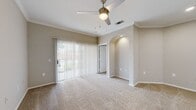 This one-bedroom, one-bathroom unit offers a well-organized single-floor layout designed to maximize functionality within a compact footprint. The living area is the focal point of the unit, featuring plush carpeting, crown molding, and a ceiling fan with an integrated light fixture that provides both comfort and illumination. A full-width sliding glass door fitted with vertical blinds floods the space with natural light and provides outdoor access. A distinctive arched architectural detail on one wall adds visual interest and serves as a design element that elevates the overall aesthetic.

The kitchen is thoughtfully appointed with stainless steel appliances, including a refrigerator, electric range, microwave, and dishwasher. Light grey shaker-style cabinetry pairs with white quartz countertops and a subtle tile backsplash, while light wood-tone vinyl flooring ties the space together with a clean, modern feel.

The bedroom offers a comfortable, carpeted retreat with a dedicated closet. The bathroom features wood-look vinyl flooring, a full tub and shower combination with tile surround, and a functional, understated design. The overall color palette throughout the unit is neutral and cohesive, creating a calm, move-in-ready atmosphere.