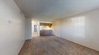 This single-story unit offers a practical and straightforward layout designed for comfortable everyday living. The open living area is finished with wall-to-wall carpet and neutral-toned walls, creating a bright and clean environment. A textured popcorn ceiling runs throughout the main living spaces, adding a classic touch to the interior.

The kitchen is positioned adjacent to the living area in a semi-open configuration, featuring warm wood-grain cabinetry on both the upper and lower levels, light-toned countertops, a white electric range with coil burners, a refrigerator, a dishwasher, and a stainless steel sink. A window above the sink allows natural light to filter into the space.

The bedrooms are carpeted and offer a calm, neutral atmosphere, each benefiting from windows that bring in natural light. Closets with sliding or hinged doors provide practical storage in the sleeping areas.

Two bathrooms serve the unit. One includes a vanity with wood cabinetry and granite-style countertops, a large mirror, and a tub-shower combination. The second bathroom is a compact space with a tub-shower unit and toilet. Both bathrooms feature tile-style flooring.