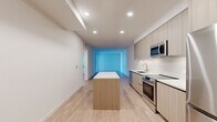 Located in San Diego's vibrant 92103 zip code, this modern 2-bedroom, 1-bathroom unit offers a thoughtfully designed single-level layout with a clean, contemporary aesthetic throughout. Light wood-tone flooring flows seamlessly across every room, complementing crisp white walls and recessed lighting that keep the space feeling bright and open.

The kitchen serves as a central hub, featuring a freestanding island with a white quartz countertop, flat-front light wood cabinetry extending to the ceiling, and a full suite of stainless steel appliances including a range, microwave, and refrigerator. The open sightlines from the kitchen extend into the living area, enhancing the sense of space.

The bedrooms are calm and functional, with clean walls and natural light provided by sliding windows. The primary bedroom includes access to a walk-in closet equipped with built-in shelving and hanging rods. The full bathroom is finished with a wood-toned vanity, white quartz countertop, a large mirror, and a tub-shower combination with floor-to-ceiling tile surround. A dedicated in-unit laundry closet houses a stacked washer and dryer, adding everyday convenience. The overall design is minimal, modern, and move-in ready.