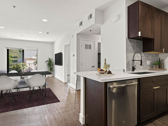 Cocina con azulejos con electrodomésticos de acero inoxidable y vista de la sala de estar con pisos de madera noble y balcón. - Bonita Terrace