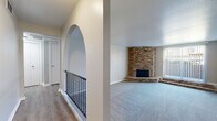 Located at 5105 N Brookline Ave in Oklahoma City, this single-floor residence offers a thoughtfully arranged layout with a blend of classic architectural character and updated interior finishes. The living room serves as the focal point of the home, showcasing a dramatic floor-to-ceiling corner brick fireplace with a raised hearth that anchors the space with warmth and visual interest. Soft blue-grey carpet spans the living area, and a large sliding glass door with vertical blinds allows natural light to filter in while providing access to an outdoor view. A distinctive arched wall detail with iron railing adds architectural charm to the entryway transition.

The kitchen features grey cabinetry with modern hardware, white quartz-style countertops, a white subway tile backsplash, and black stainless appliances including a gas range, dishwasher, and refrigerator. Light wood-look flooring completes the clean, functional aesthetic.

The bedrooms are carpeted and neutral in tone, each offering ceiling fans and natural light from windows with blinds. At least one bedroom includes a walk-in closet. The bathroom is outfitted with wood-look flooring, a tub-shower combination with a subway tile surround, and a vanity with marble-look countertops and grey cabinetry.