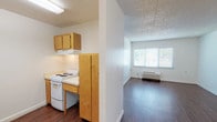 This single-floor, one-bedroom, one-bathroom unit is thoughtfully designed with accessibility in mind. Dark hardwood-style flooring runs throughout the main living areas, creating a cohesive and easy-to-navigate layout. The living room is bright and open, featuring a large window that invites natural light and outdoor views, complemented by a ceiling fan and a wall-mounted HVAC unit for year-round comfort. A textured ceiling adds dimension to the space.

The galley-style kitchen is efficiently arranged with warm wood cabinetry, light countertops, a white electric range, and a stainless steel sink. Upper cabinets provide ample storage, and the open passthrough connects the kitchen seamlessly to the living area.

The bedroom offers a generous footprint with a wide window fitted with blinds, a ceiling fan, and the same rich flooring found throughout the unit, providing a calm and comfortable retreat.

The bathroom is fully ADA-compliant, equipped with strategically placed stainless steel grab bars, a roll-in shower with a built-in bench, a separate bathtub, and a wall-mounted sink — all designed to ensure safe and independent use. The white tile flooring and walls create a clean, accessible environment.

Overall, this unit combines practical accessibility features with a clean, functional design.