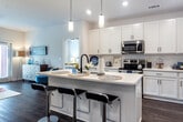 Located at 10952 Netherly Dr in Charlotte, NC, this single-story home showcases a clean, contemporary design with wood-look flooring, neutral walls, and recessed lighting throughout. The open-concept kitchen is a standout feature, outfitted with crisp white shaker cabinets, a classic subway tile backsplash, quartz countertops, stainless steel appliances, and a large center island with pendant lighting and bar seating — ideal for both cooking and entertaining. The living area offers a bright, welcoming atmosphere with abundant natural light from large windows and a glass door that opens to an outdoor space, creating a seamless indoor-outdoor connection. The primary bedroom is generously sized with plush carpet, large windows overlooking greenery, a ceiling fan, and a private en-suite bathroom featuring a soaking tub, wood-look flooring, a white vanity, and direct access to a walk-in closet. A second full bathroom serves additional rooms and mirrors the same clean, modern aesthetic with a tub-shower combination. A dedicated office or flex room with carpet flooring offers versatility for a home workspace or additional bedroom. Throughout, the home maintains a cohesive, move-in-ready feel with thoughtful finishes and ample storage.