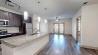 This contemporary apartment in Villaggio offers a harmonious blend of style and functionality across its 1010 square feet. The open-concept design seamlessly integrates the kitchen, living, and dining areas, creating a spacious feel. The kitchen boasts dark wood cabinetry, granite countertops, and stainless steel appliances, including a built-in microwave. A large island with a breakfast bar provides additional prep space and casual seating.

Both bedrooms are generously sized, with the primary bedroom measuring 160 square feet. Arched windows in the bedrooms allow ample natural light and offer picturesque views. The bathrooms feature modern fixtures, granite vanity tops, and a combination of tile and wood-look flooring. Ample closet space is available throughout the apartment.

The living areas are adorned with wood-look flooring, while the bedrooms are carpeted for comfort. Ceiling fans and recessed lighting add both functionality and ambiance. The apartment's neutral color palette provides a versatile backdrop for various decor styles. With its thoughtful layout and high-quality finishes, this Villaggio apartment offers a luxurious and comfortable living experience.